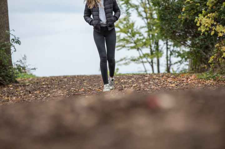 woman in black leggings while walking on brown road